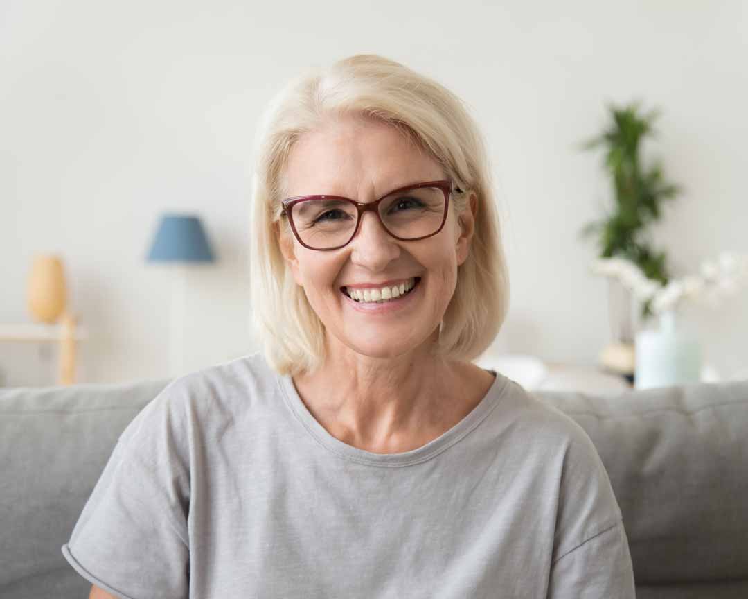 Older woman with blonde hair and red glasses smiling